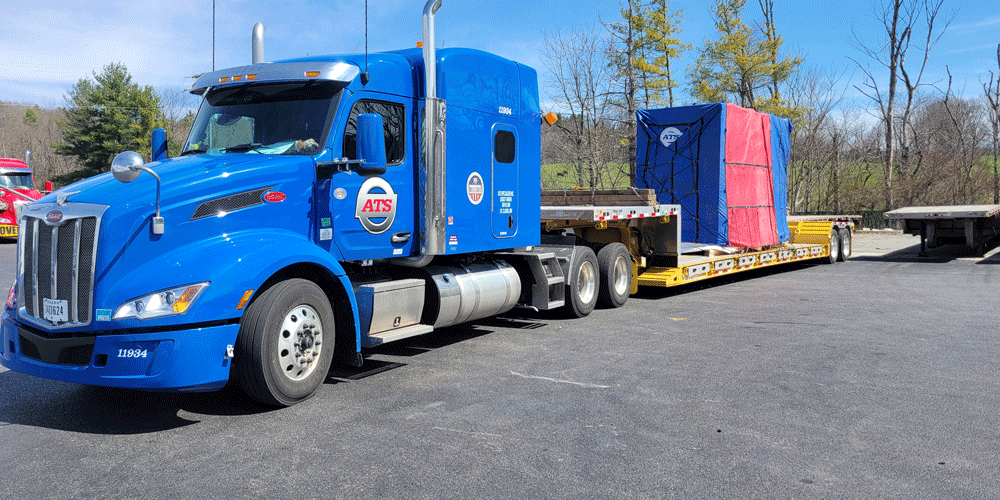Blue ATS truck with a step-deck tarped load.