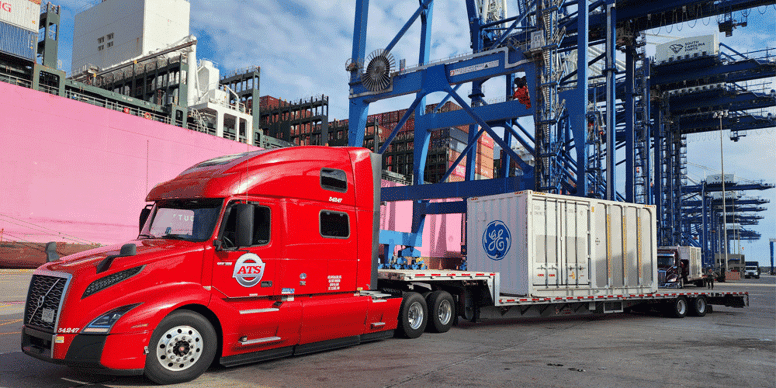 A red ATS flatbed truck at port hauling container