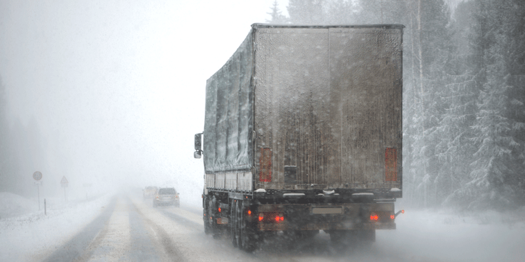 Van truck navigating a snowy, wintry road.