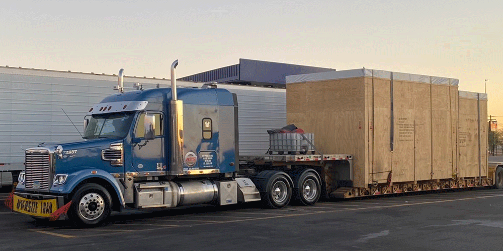 Blue ATS truck hauling two large wooden boxes.