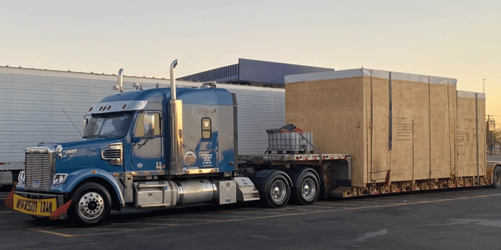 Blue ATS truck hauling two large wooden boxes.