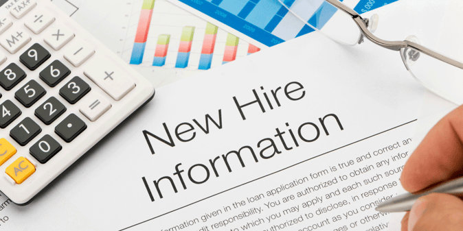 Piece of paper that says "New Hire Information." It lies near accounting sheets, a calculator, and glasses.