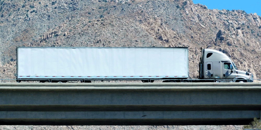 Semi-truck driving on overpass. 