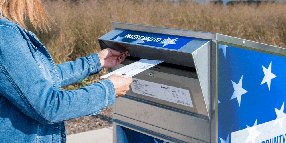 Placing a ballot into a mailbox.