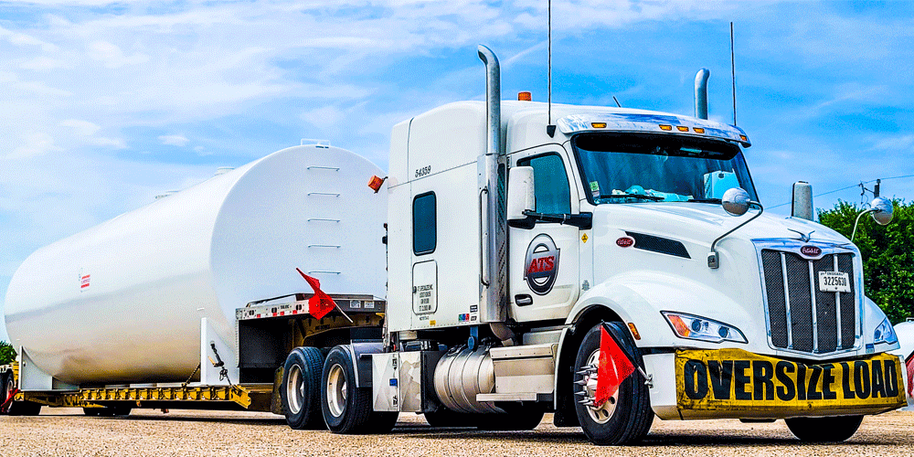 White ATS truck hauling oversized white tank.