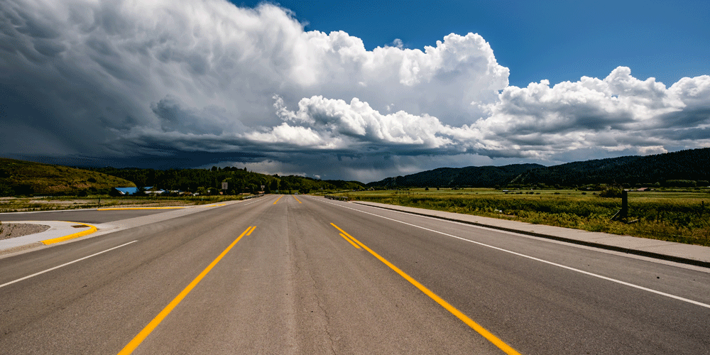 An empty open highway and a cloudy sky.