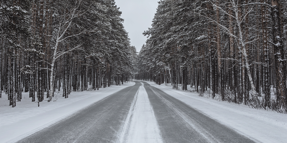 A snow-covered road with snow-covered trees on each side.