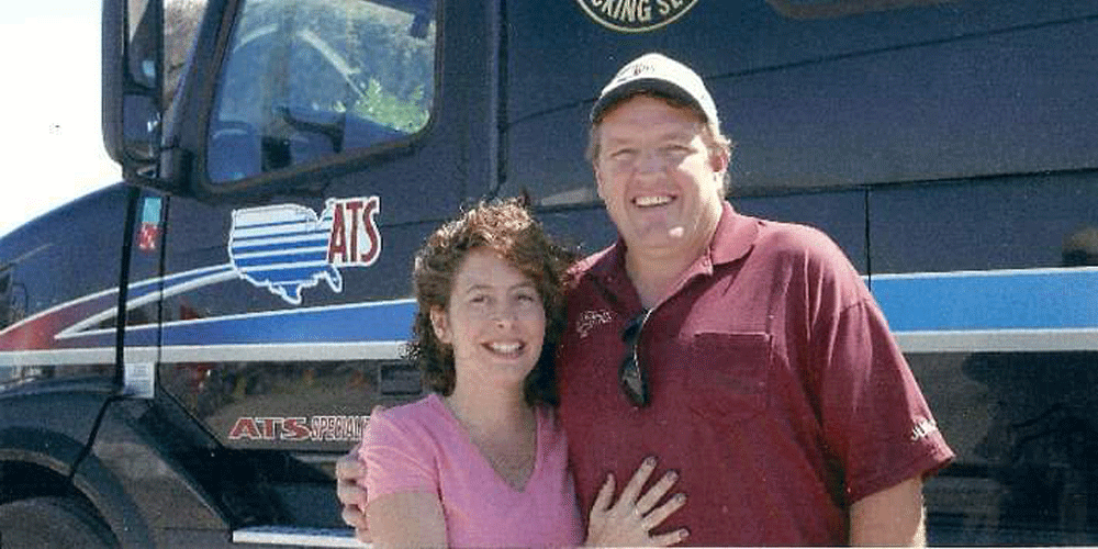 Married team of truck drivers in front of their truck.