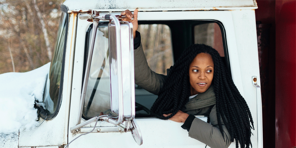 Woman with long hair hanging out the window of her truck.