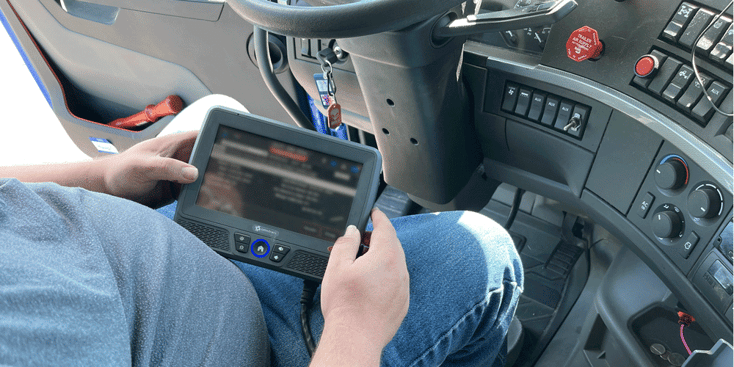 Truck driver checking his electronic logging device (ELD) in truck