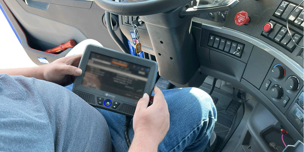 Driver in their driver's seating looking at their elogs on their ELD.
