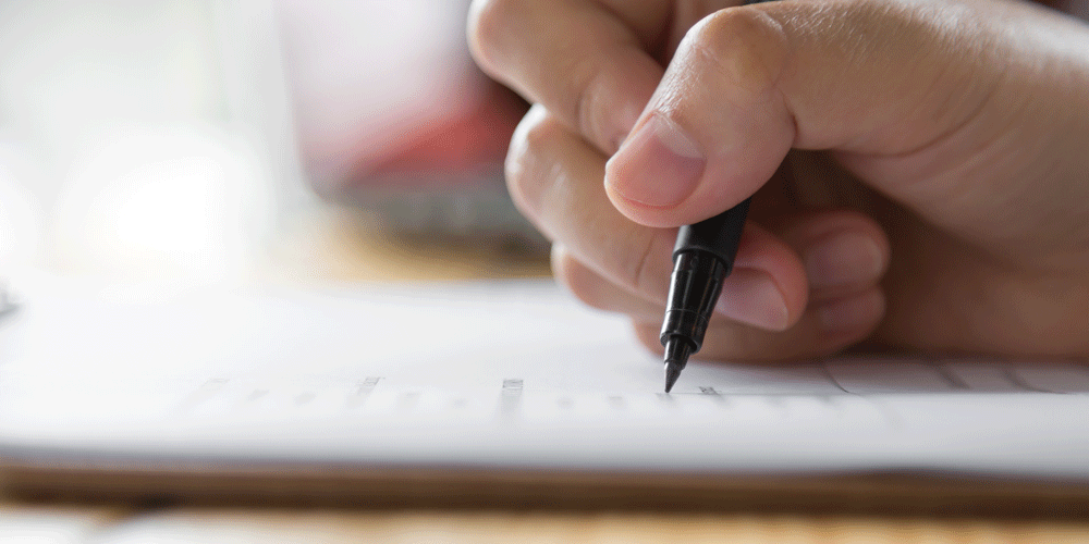 Close up of a hand writing on paper with a pen.