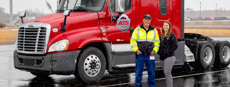 ATS driver standing with his driver manager beside his parked semi-truck; highest-paying trucking companies; Anderson Trucking Service