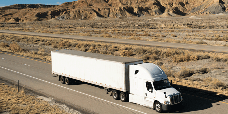 White semi and dry van driving in desert mountains, navigating headhaul and backhaul markets