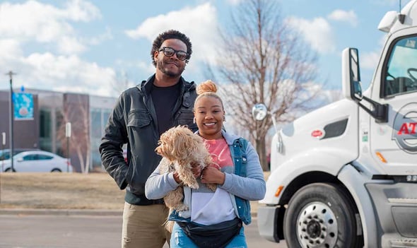 A man and a woman holding a dog stand outside ATS headquarters; best dry van trucking companies to work for; Anderson Trucking Service
