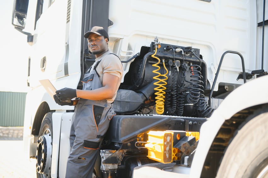 A truck mechanic reviews a scope of work on a laptop